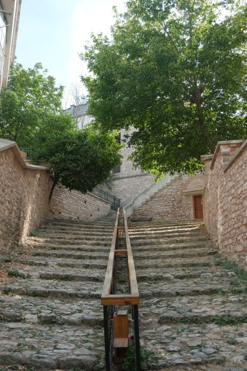 Free Old stone staircase lined with walls leads up to a historical building surrounded by trees. Stock Photo