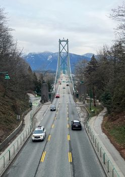 Lions Gate Bridge with traffic, framed by mountains in late winter.