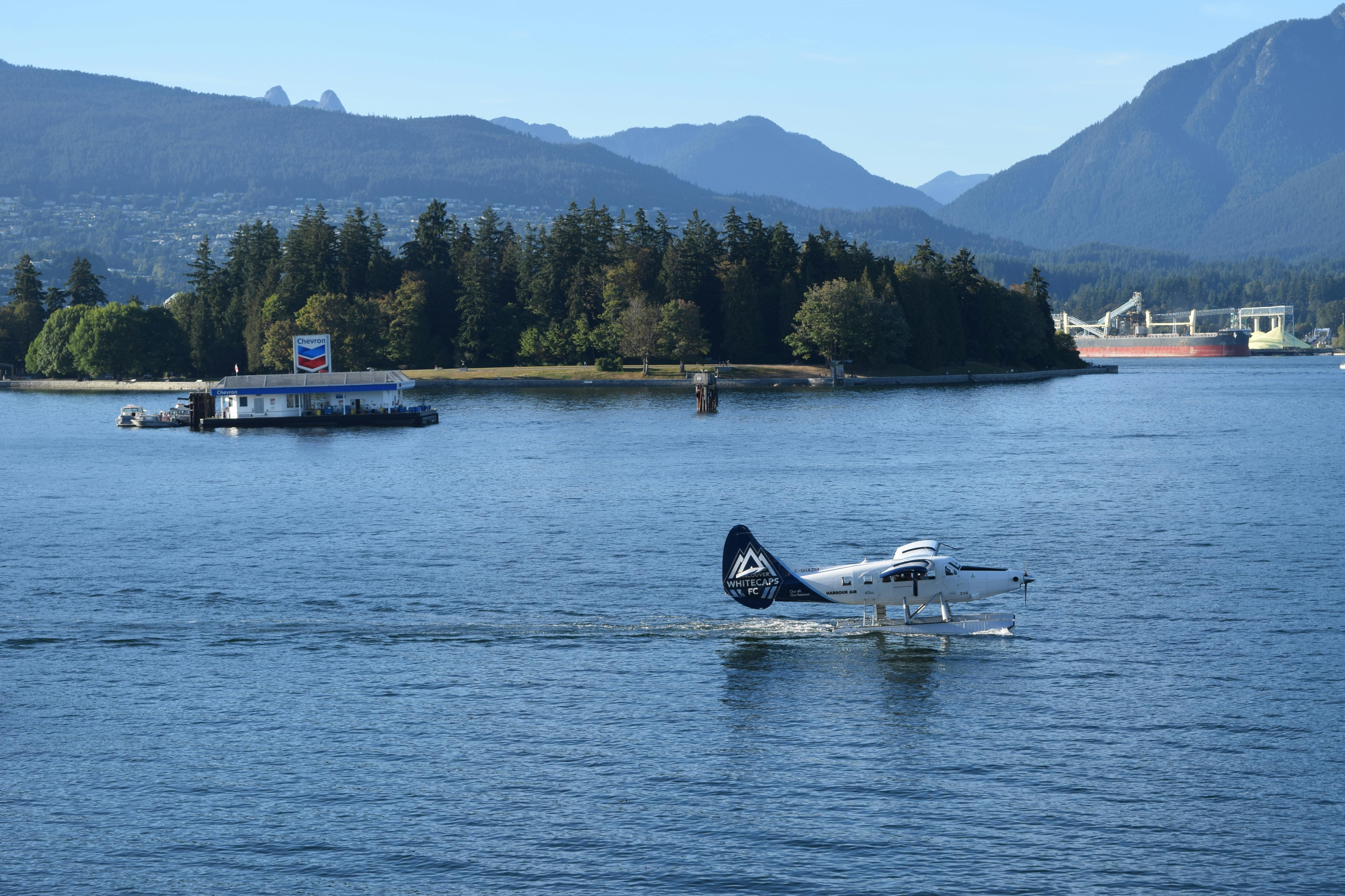 A seaplane navigating a picturesque bay surrounded by mountains and lush forests.