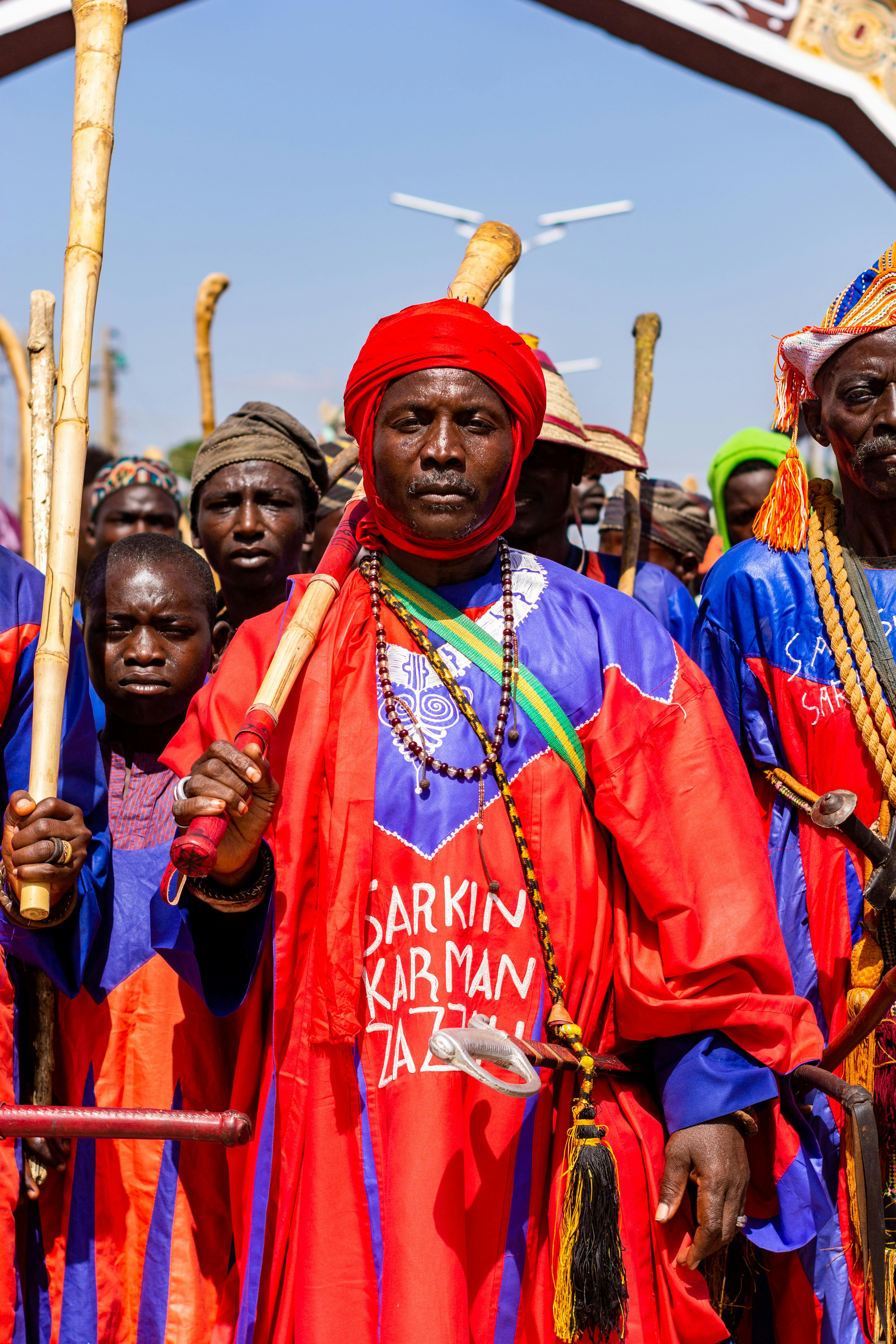 A group of people in colorful traditional attire participating in a cultural festival outdoors.