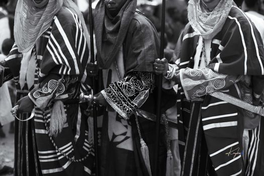Black and white photo of people in traditional African attire during a cultural ceremony.