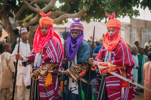 Colorfully dressed individuals in traditional African attire participating in a cultural parade outdoors.