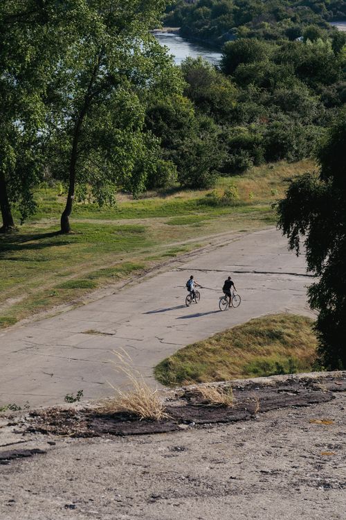 Free Two cyclists ride on a sunny day in rural Kaliningrad Oblast, Russia, highlighting the summer landscape. Stock Photo