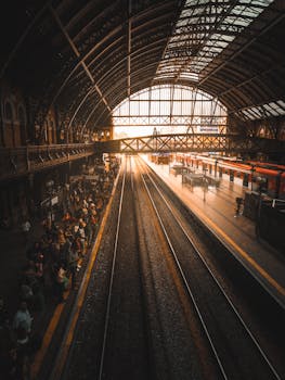 日落时分，阳光透过拥挤火车站的屋顶，照在等待的通勤者身上