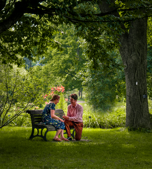Free A couple sharing a romantic moment on a park bench in a lush summer setting in Montreal, Canada. Stock Photo