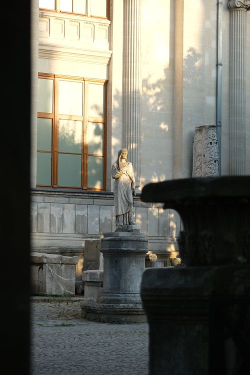 Free A serene statue in a historic courtyard under soft evening light, casting dramatic shadows. Stock Photo
