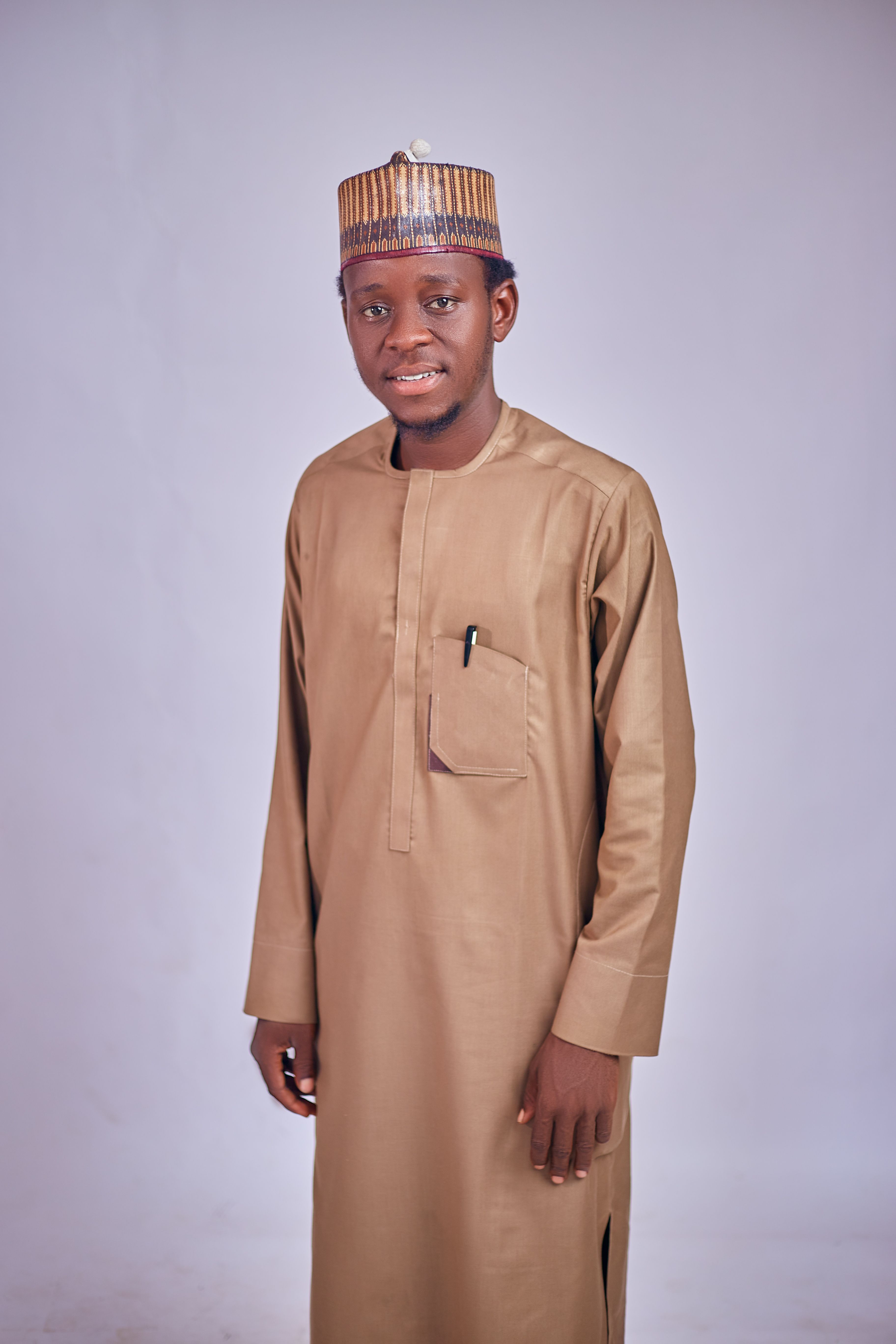 Smiling young man in beige traditional attire posing against a neutral background.
