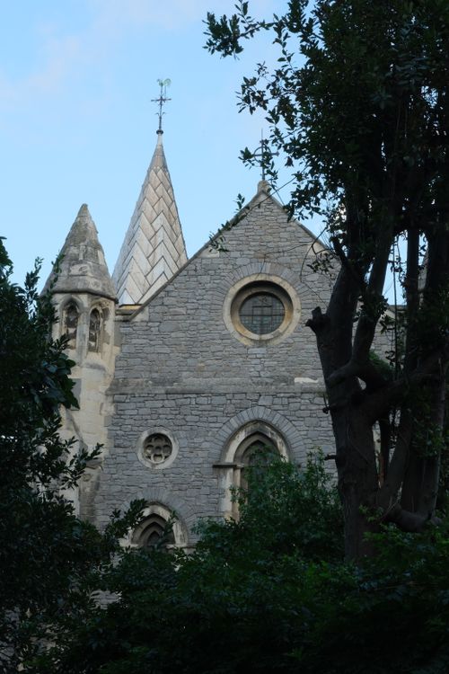 Free A historic stone church with architectural details behind lush greenery. Stock Photo