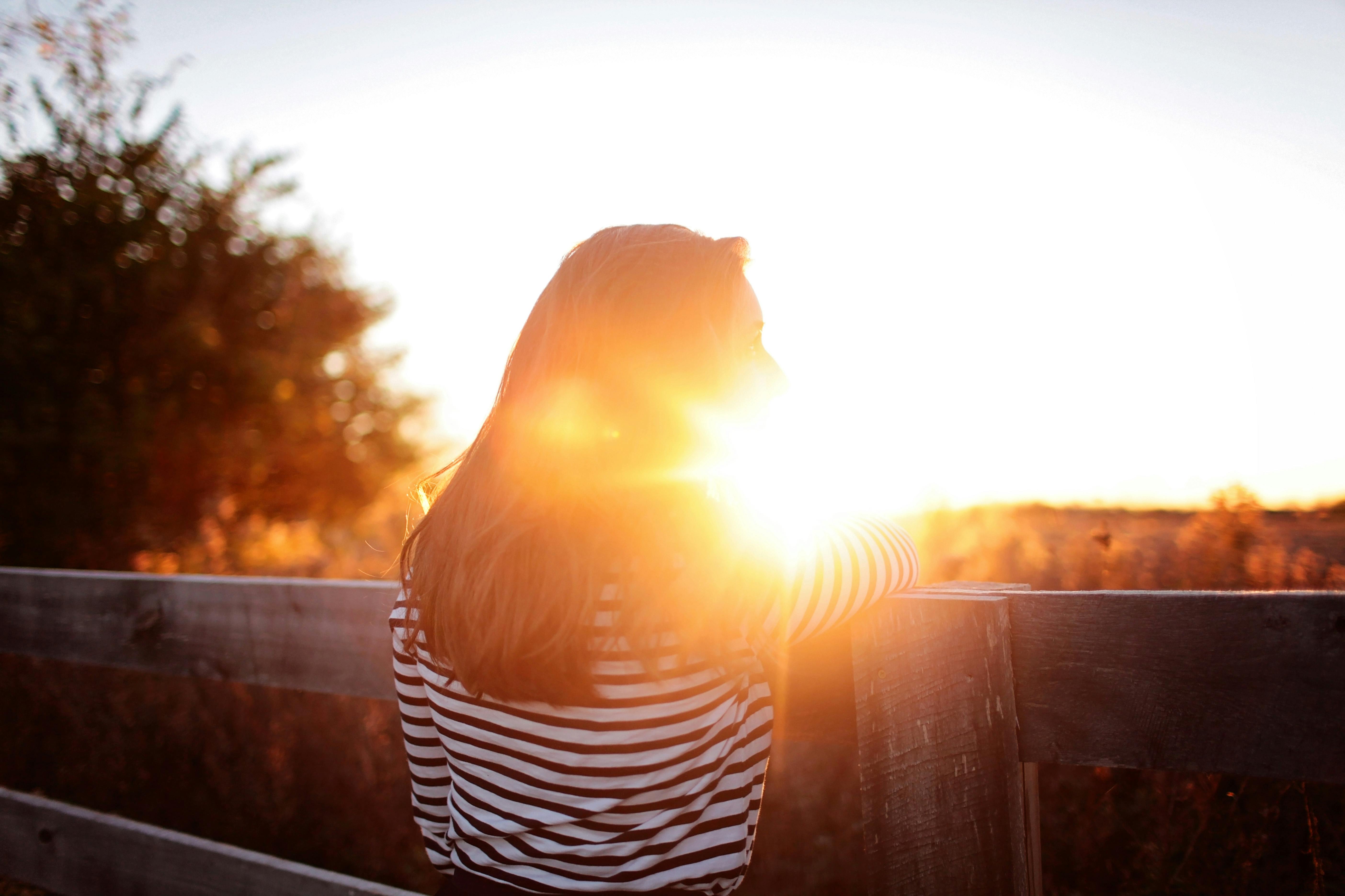 Vista Trasera De La Mujer De Pie En El Balcón Durante La Puesta De Sol · Fotos de stock gratuitas