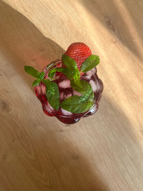 Free Top view of a refreshing strawberry mint iced drink in a glass on a sunny wooden table. Stock Photo