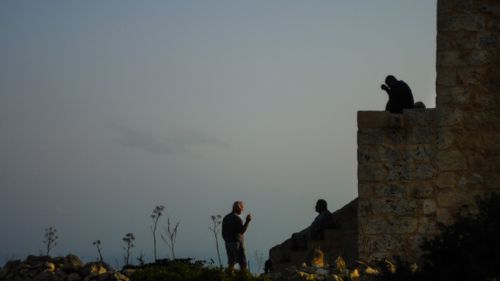 Free Silhouetted figures converse by an ancient wall in Malta at sunset, evoking a serene and historical vibe. Stock Photo