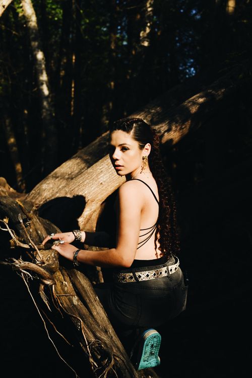 Free Artistic shot of a young woman in forest, captured with dramatic lighting and natural elements. Stock Photo