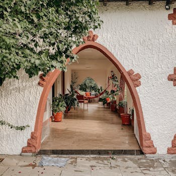 Cozy home entrance featuring an elegant red archway, vibrant greenery, and rustic designs, perfect for a serene lifestyle.