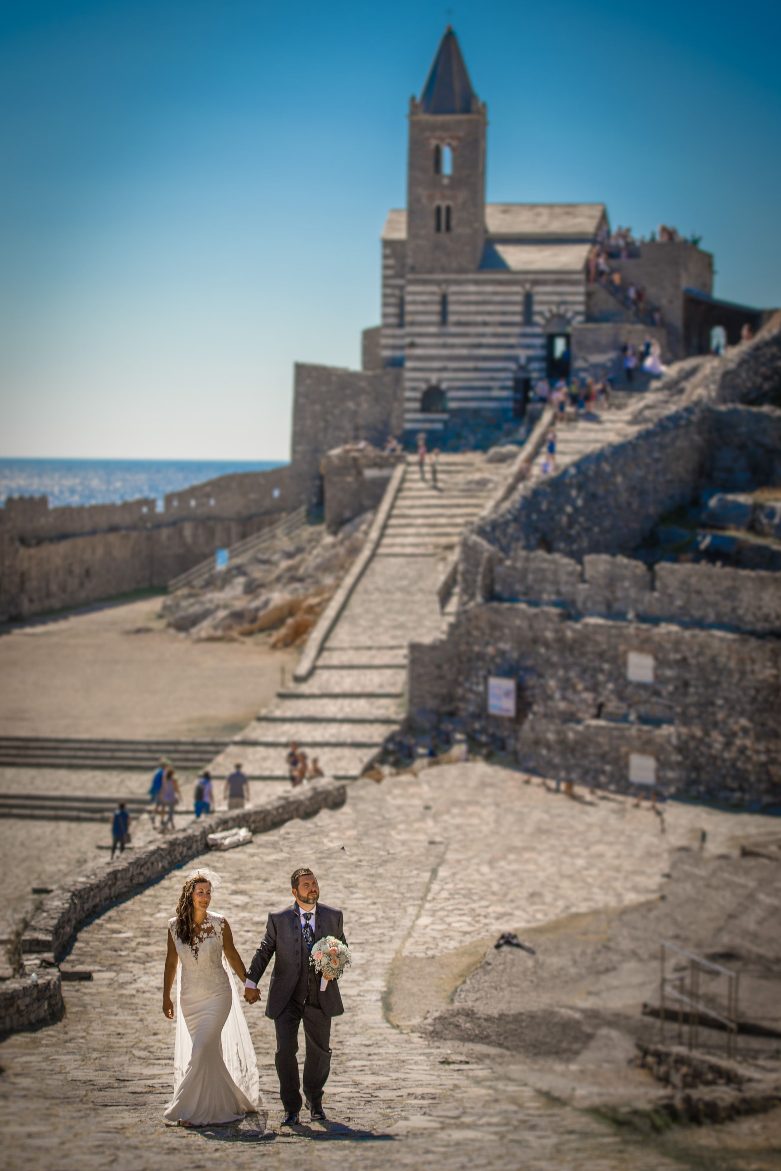 Stunning bridal couple walking at the historic Portovenere Church, Liguria, Italy.
