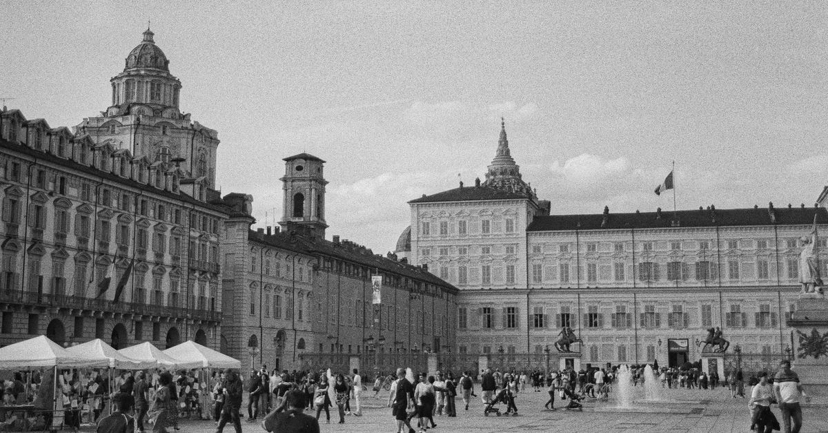 Monochrome view of Piazza Castello in Turin, Italy, showcasing historic architecture and vibrant public life.