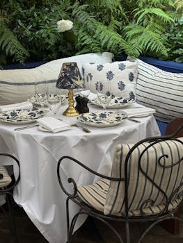 Charming outdoor cafe setting with elegant tableware and lush green ferns.
