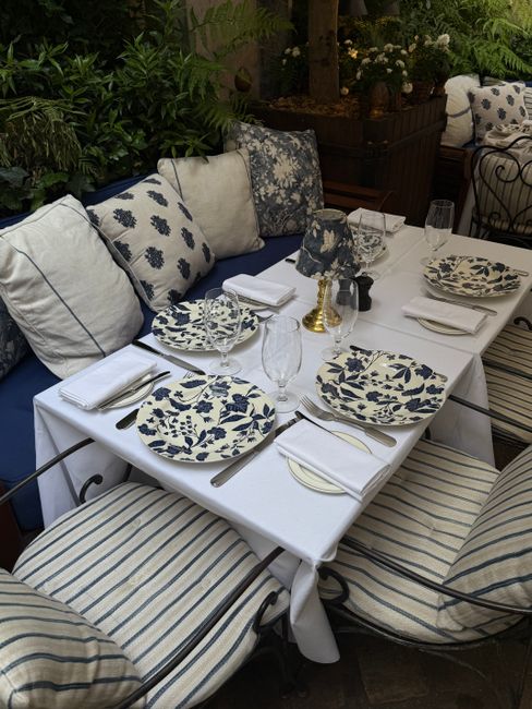 Stylish outdoor dining setup with floral plates and striped cushions.