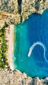 Aerial view of a stunning beach bordered by vibrant blue sea and rocky cliffs.