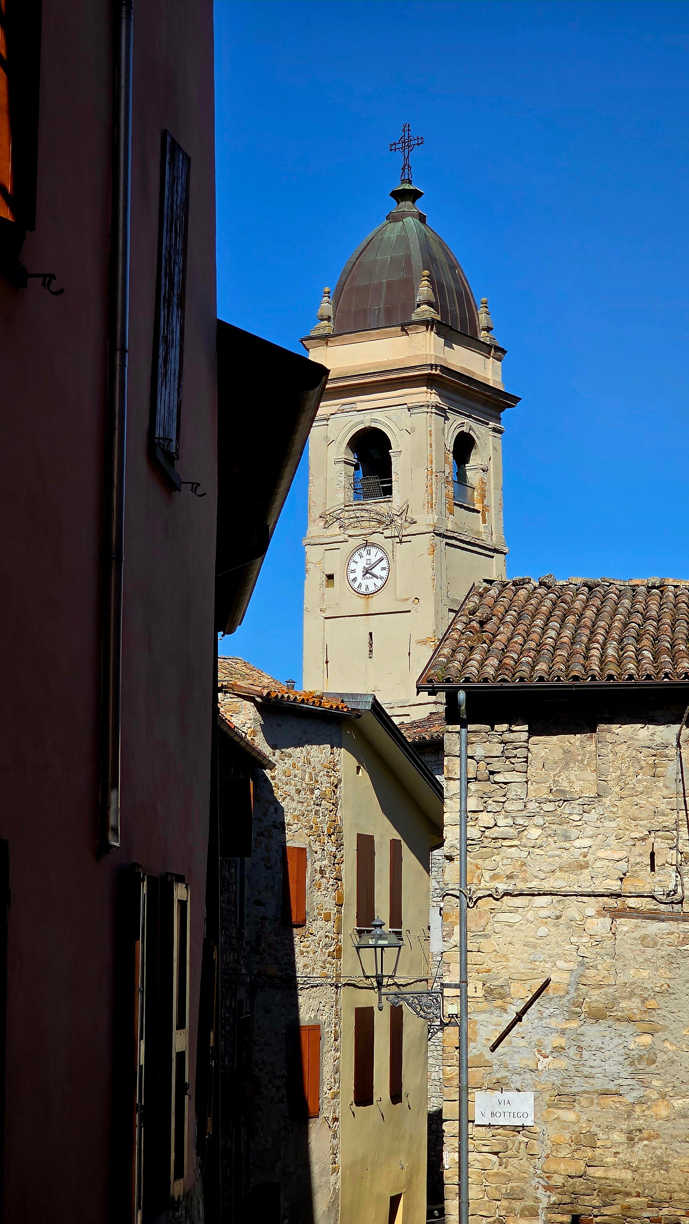 A picturesque Italian village scene showcasing a historic bell tower and traditional stone buildings.