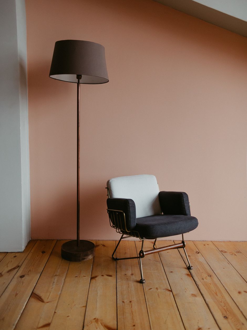 Sophisticated minimalist interior featuring a stylish lamp and modern chair against a pastel wall.