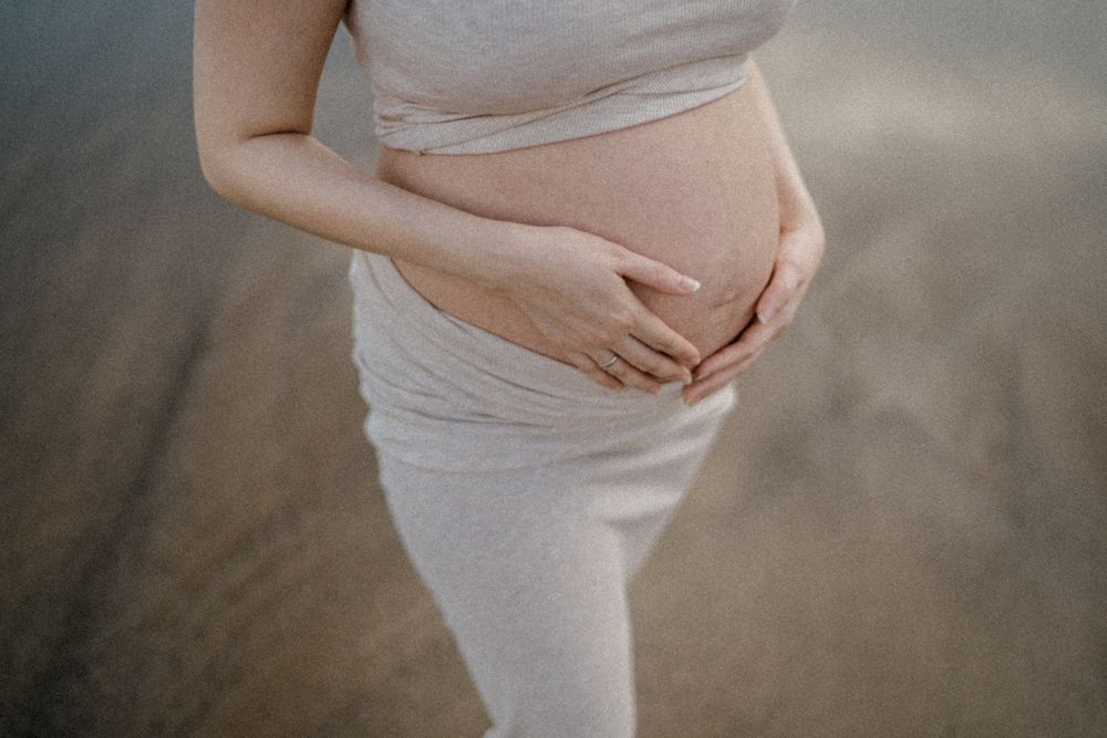 Mujer embarazada sosteniendo su vientre con serenidad al aire libre