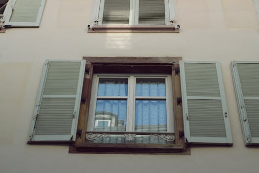 Elegant facade featuring light green shuttered windows and ornate details, capturing a timeless architectural style.