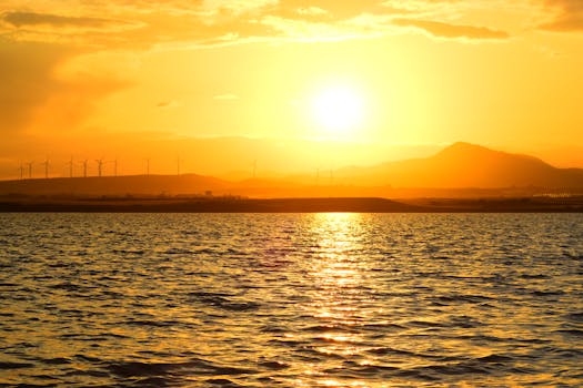 Stunning sunrise over Larnaca Bay with wind turbines and golden reflections on the water.
