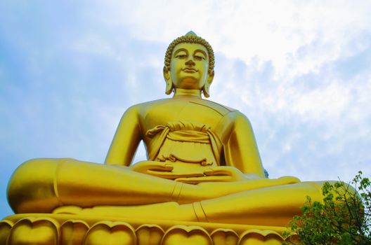 Majestic golden Buddha statue photographed under a bright sky, emphasizing serenity and peace.