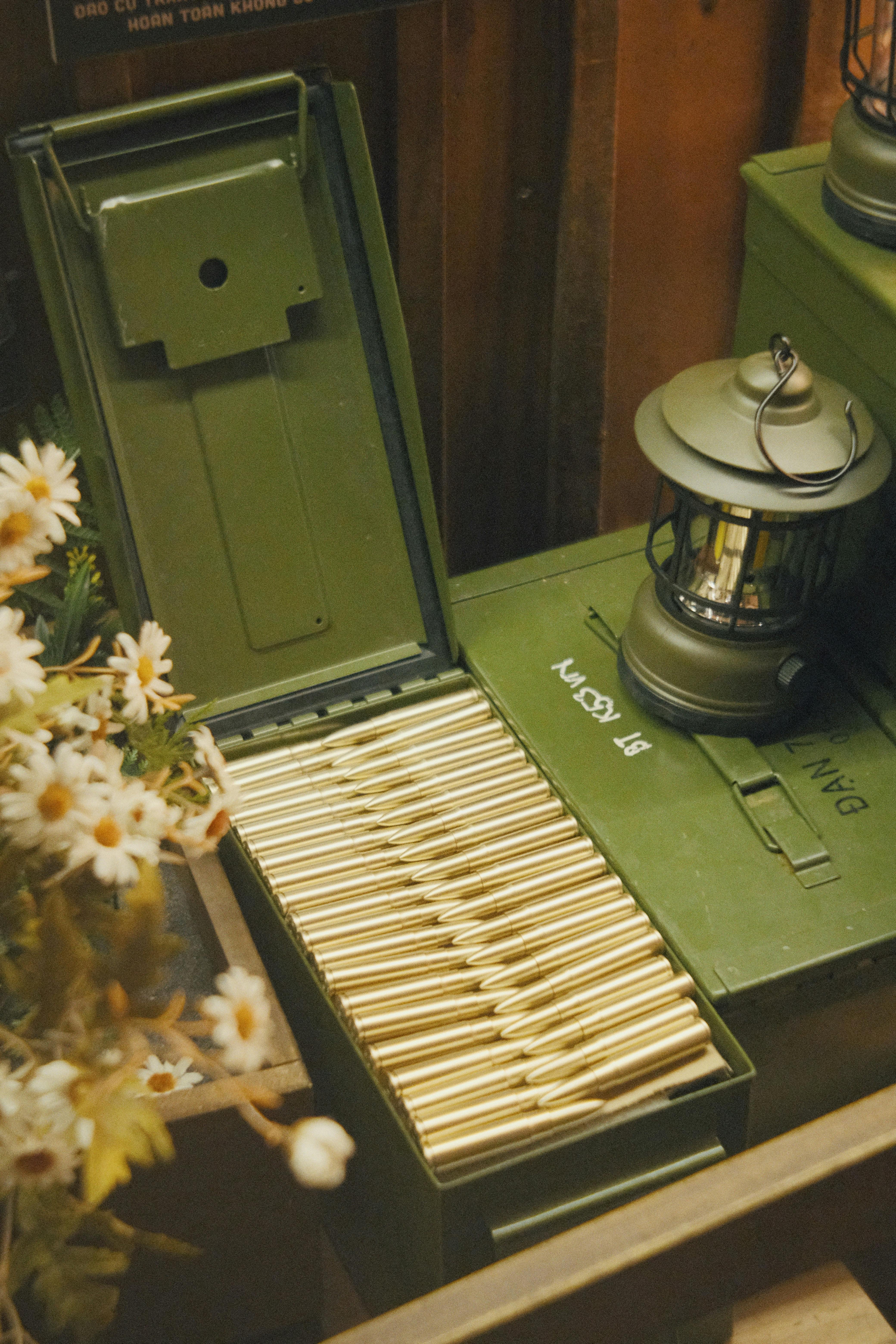 Open ammo box and lantern displayed with daisies for vintage military decor.