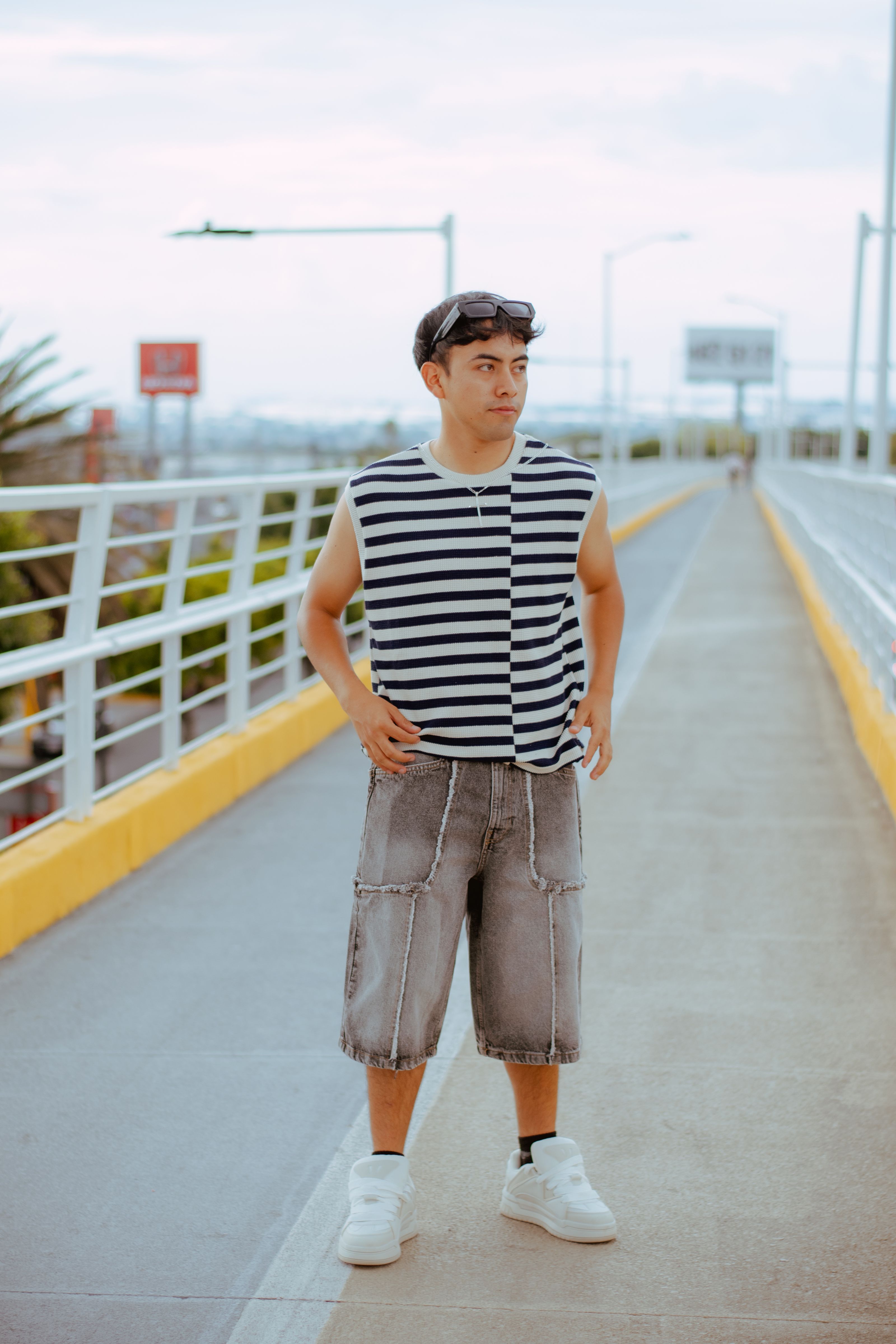 Jovem vestido com uma roupa casual listrada em uma moderna passarela urbana durante o dia.