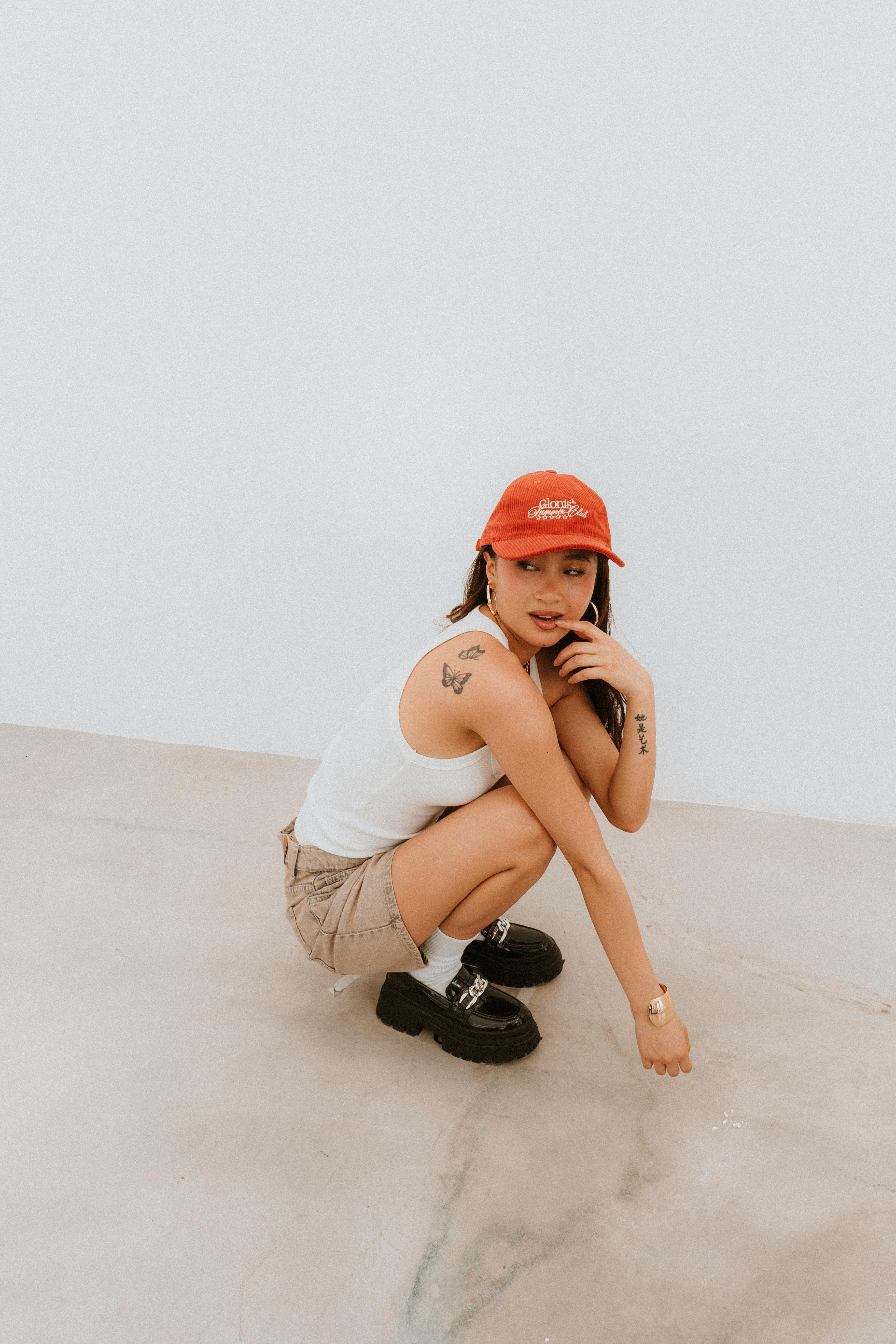 De franc Una dona moderna amb roba informal d'estiu posa amb confiança a l'interior, mostrant un estil urbà modern. Foto d'estoc