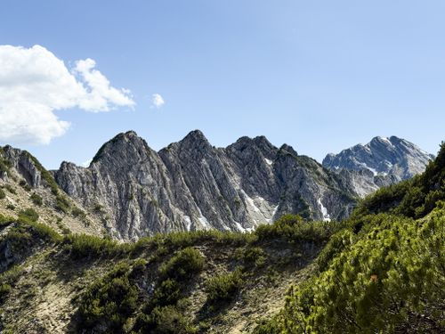 Free Dramatic jagged mountain peaks with lush greenery under a vibrant blue sky, perfect for nature enthusiasts. Stock Photo
