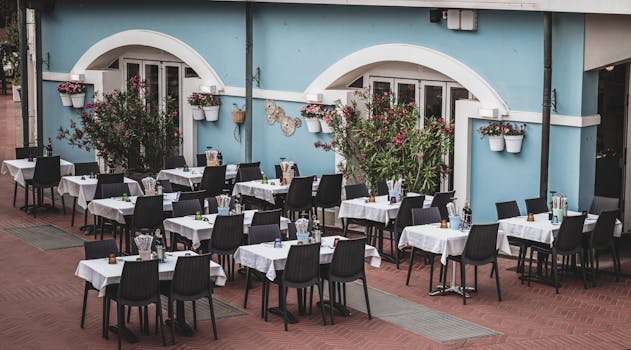 Cozy outdoor cafe with neatly arranged tables and a vibrant blue facade, perfect for dining.