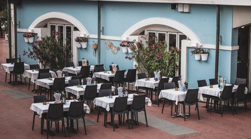 Free Cozy outdoor cafe with neatly arranged tables and a vibrant blue facade, perfect for dining. Stock Photo