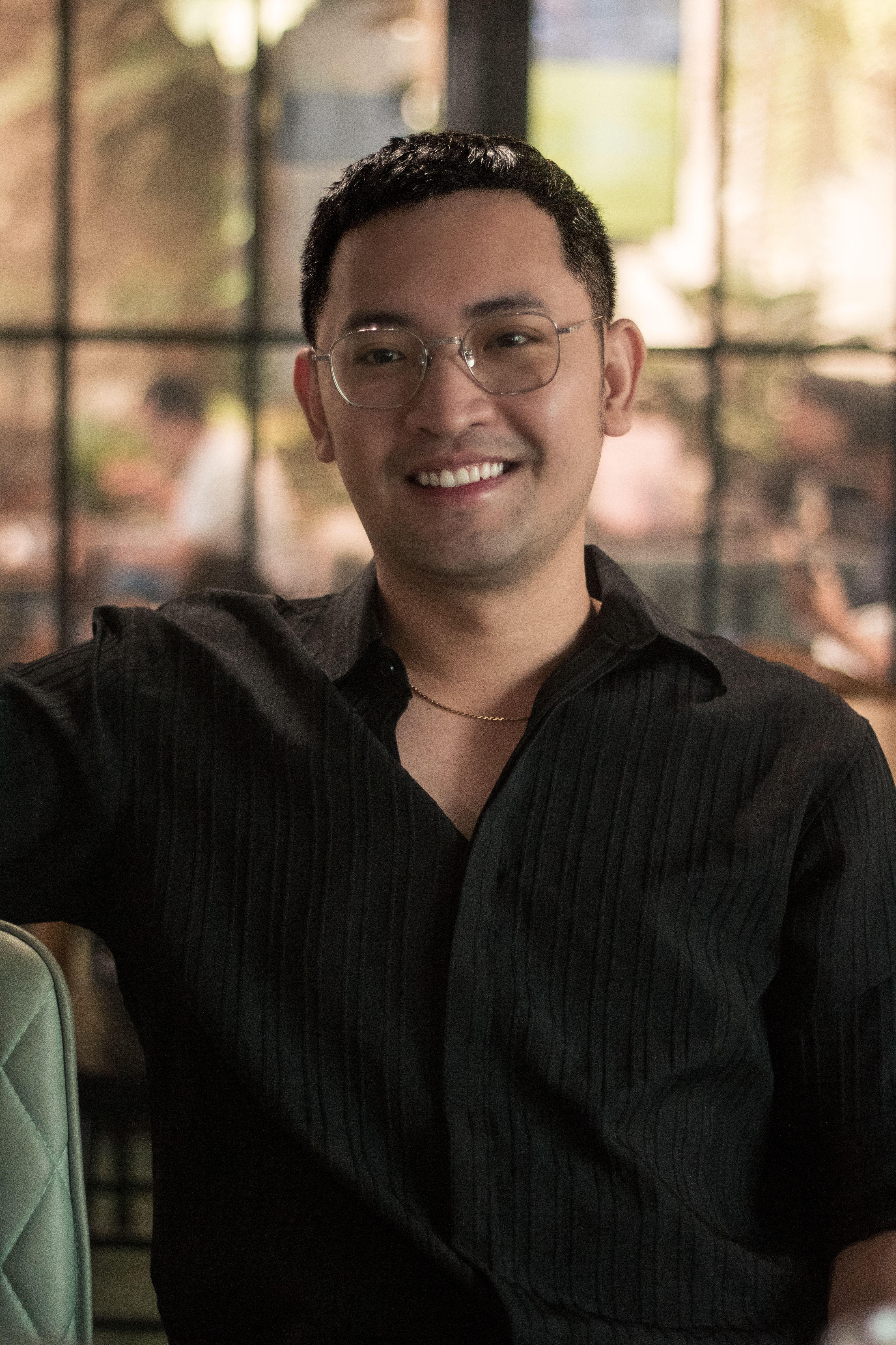Smiling man in casual indoor cafe environment captures warmth and style.