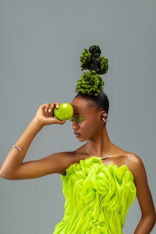 Free Artistic portrait of a woman with a green apple and vibrant dress. Stock Photo