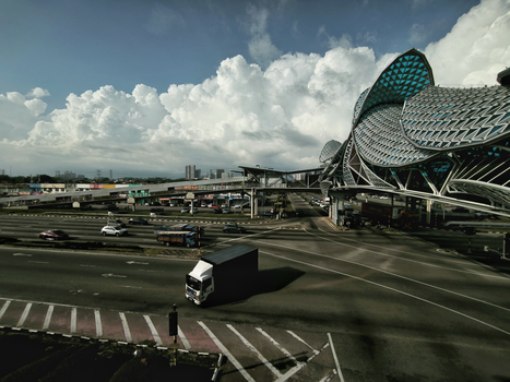 Dynamic view of a highway intersection with modern architectural structure and cloudy sky.