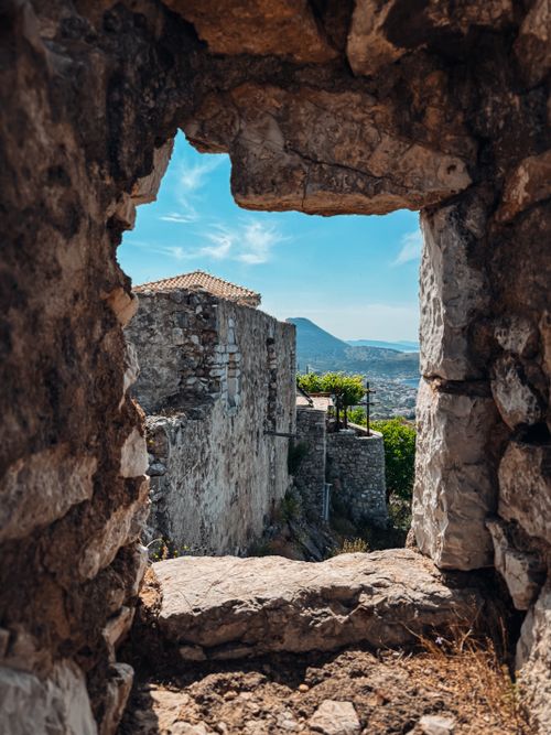 Free A scenic view of the Albanian landscape through a stone window of an ancient fortress. Stock Photo