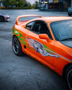 Bright orange Toyota Supra with custom graphics showcased in Ankara, Türkiye, exuding a sporty vibe.
