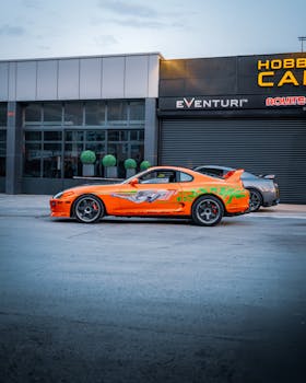 Bright orange Toyota Supra parked in front of a car shop in Ankara, Türkiye, during the day.