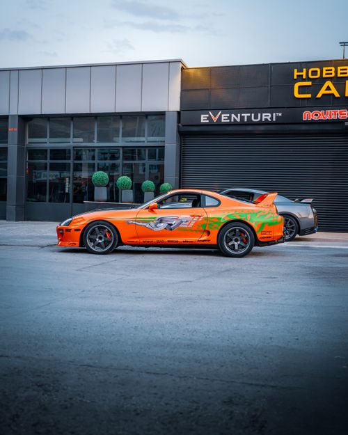 Free Bright orange Toyota Supra parked in front of a car shop in Ankara, Türkiye, during the day. Stock Photo