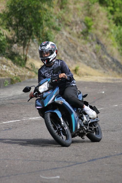 Free Motorcyclist in protective gear navigating a curve on a scenic road. Stock Photo