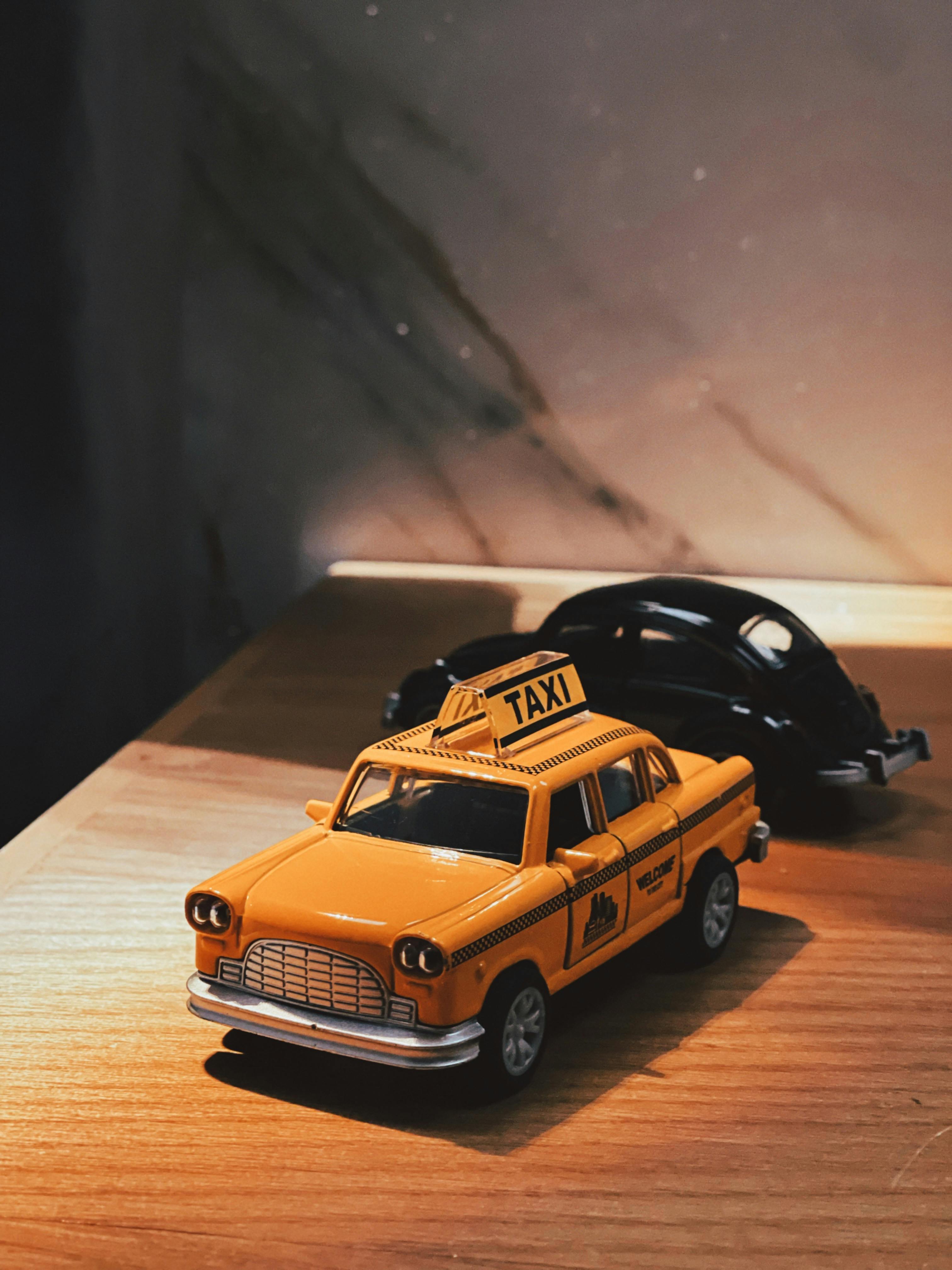 Gratis Sebuah taksi dan mobil mainan kuning kuno terletak di permukaan kayu, diambil dalam pencahayaan yang hangat. Foto Stok