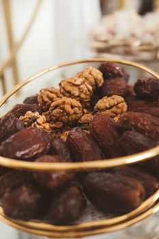 A golden bowl filled with dried dates and walnuts, perfect for a healthy snack.