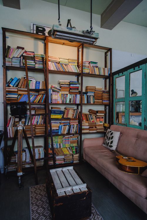 Free Inviting home library with wooden shelves, books, and guitar on a couch. Stock Photo