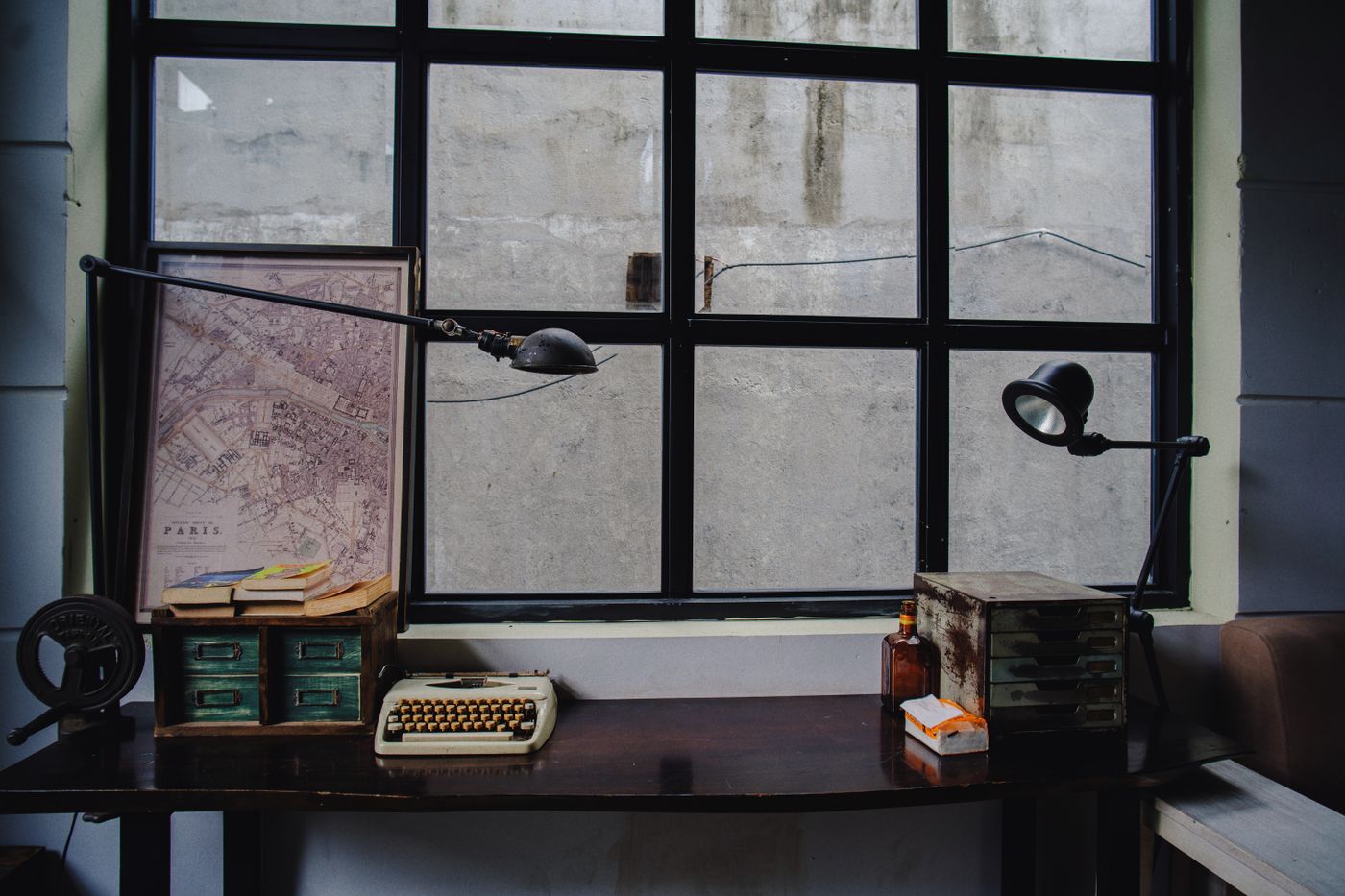 Bureau avec une machine à écrire et une carte de Paris près d'une fenêtre