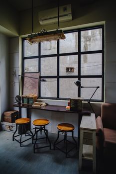 A cozy vintage-style workspace with stools and a large window. Perfect for creative work.
