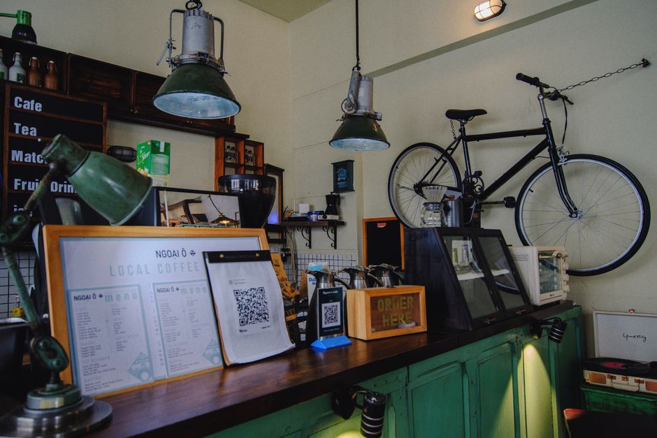 ビンテージな装飾、緑のアクセント、吊り下げられた自転車が特徴の、魅力的な地元のコーヒーショップ。