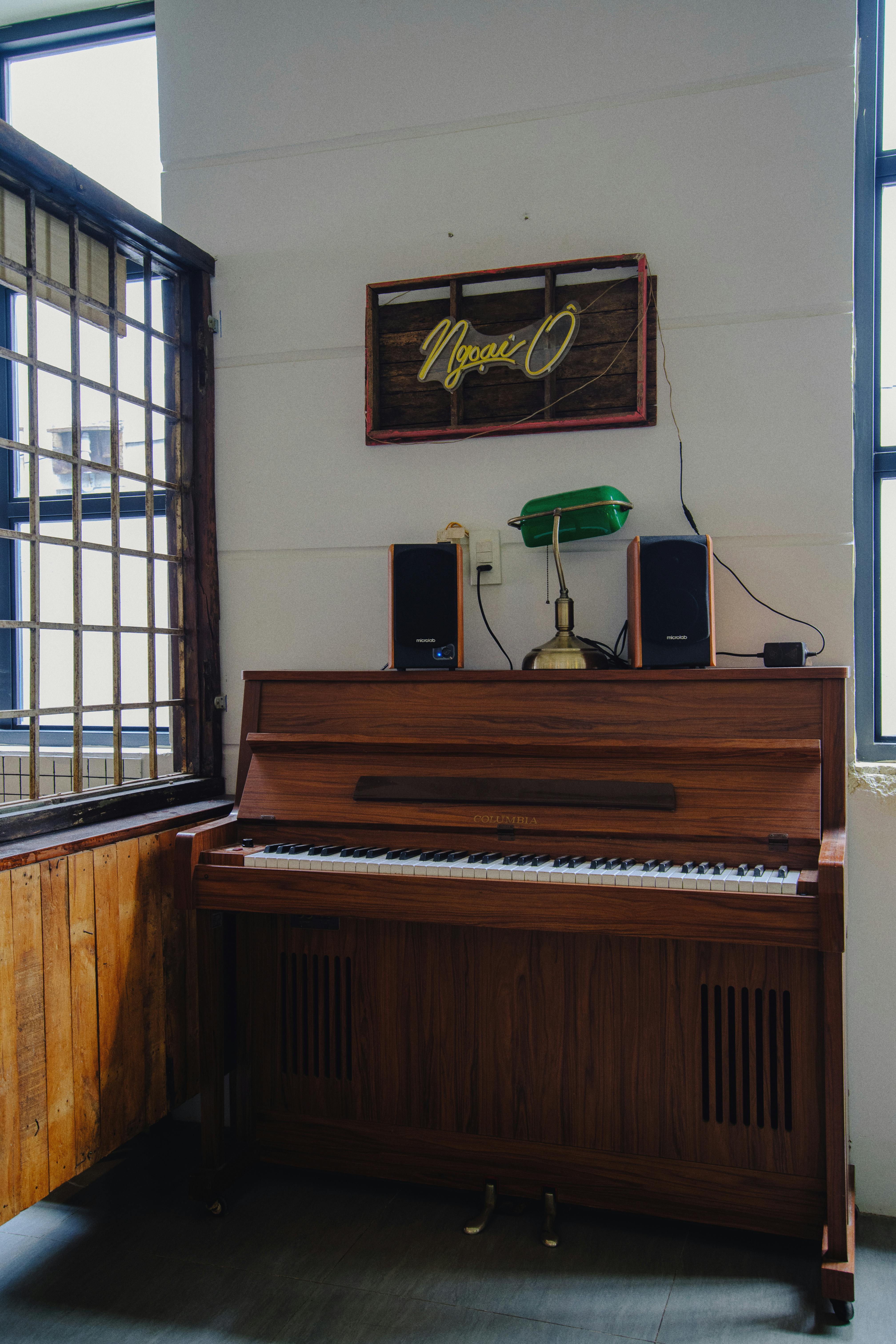 Free An inviting indoor space featuring a wooden upright piano and neon sign, perfect for music lovers. Stock Photo
