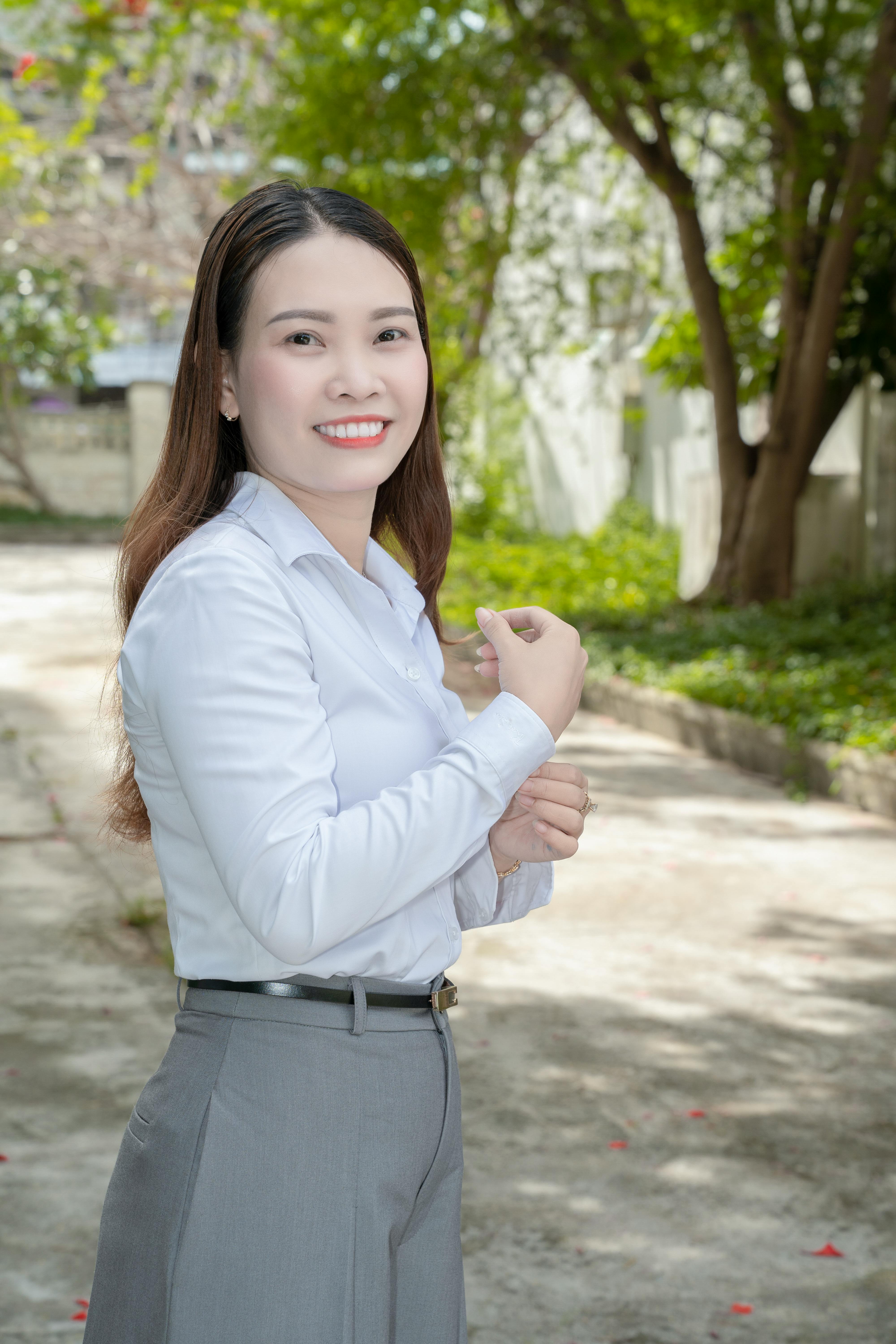 Professional woman smiling in outdoor setting with natural light and greenery.